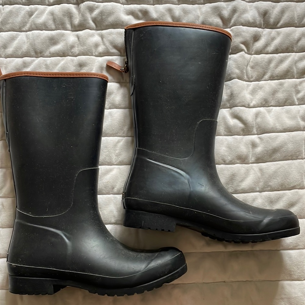 Black rain boots with a brown/tan rim, and a zipper along the back